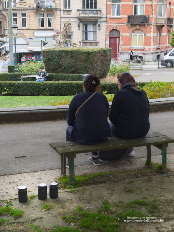 2 quidams assis sur un banc à côté de 3 sténopés